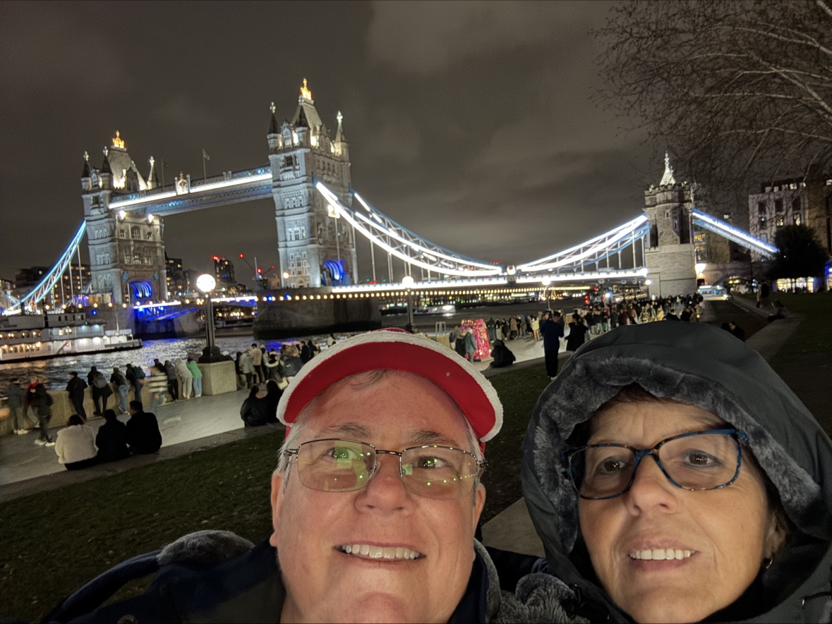 Anne and Kathy in front of Tower Bridge lit up at night, London