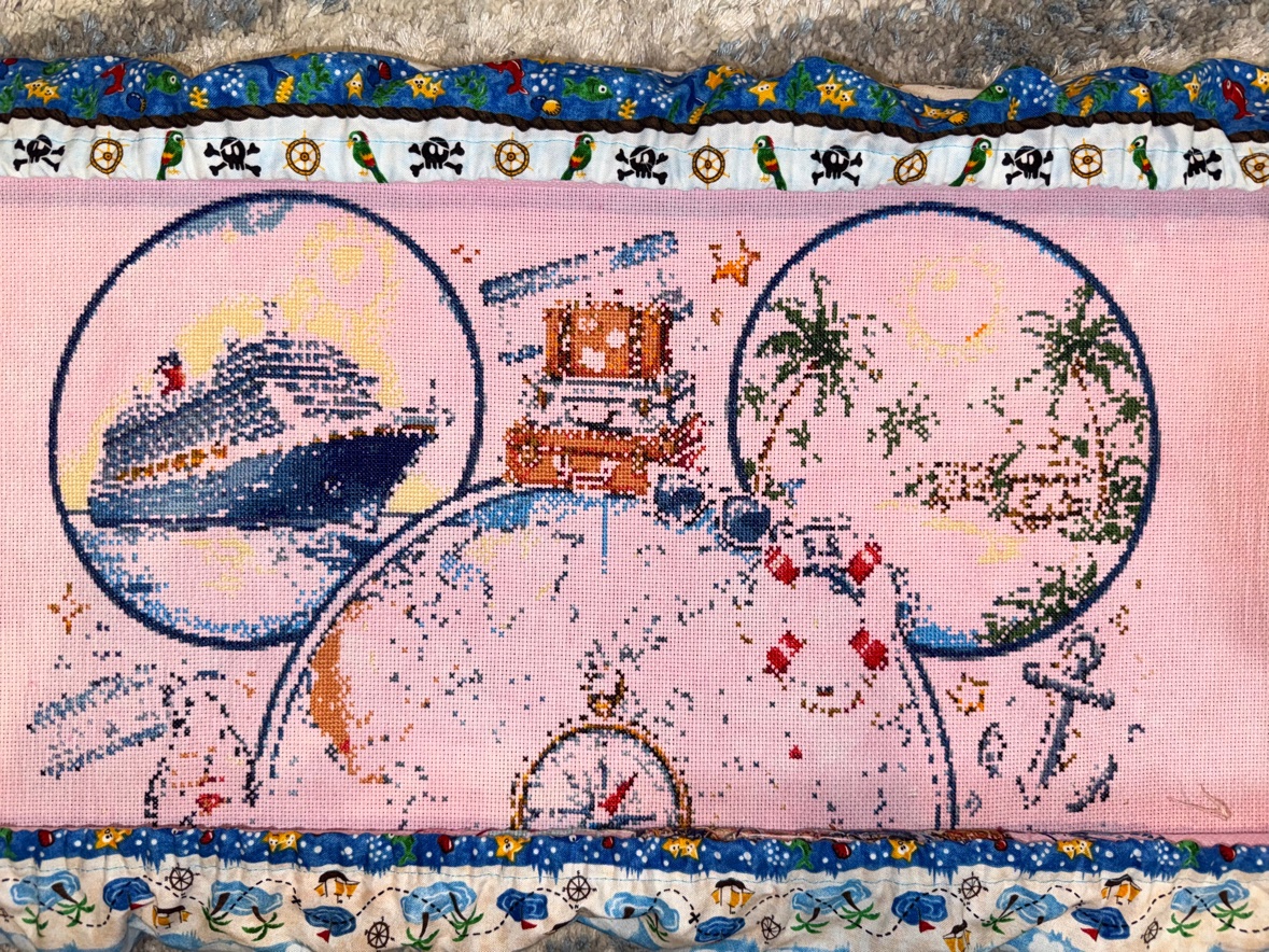 Anne Conrad&rsquo;s &ldquo;Magical Cruise&rdquo; cross stitch in progress on pink hand-dyed fabric in a scroll frame