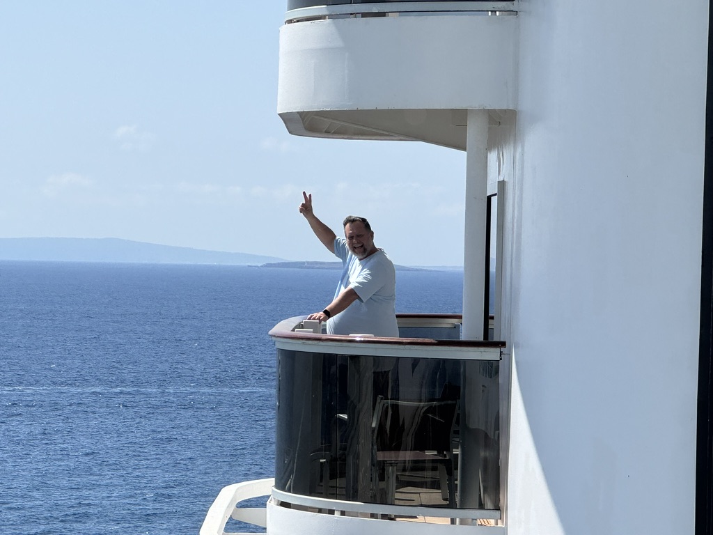 A traveler waving from the balcony of a cruise ship