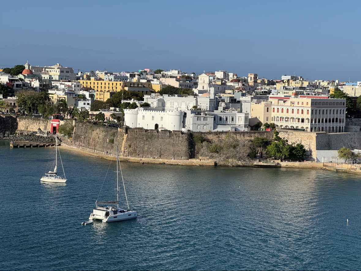 Old San Juan's city walls and colorful skyline seen from the bay, with catamarans anchored in the foreground