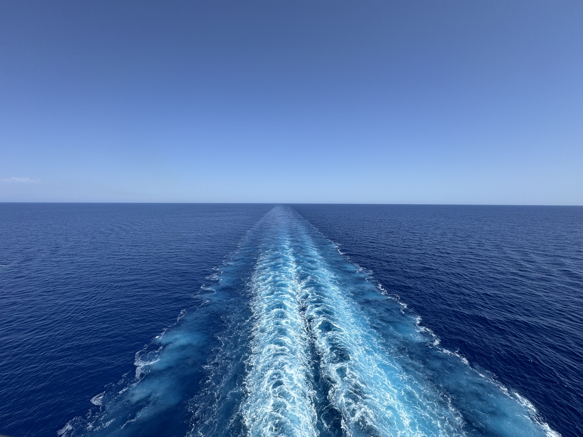 The wake of Anne's cruise ship stretching across deep blue ocean to the horizon